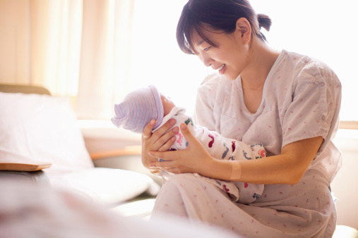 Mid adult mother holding newborn baby girl, smiling